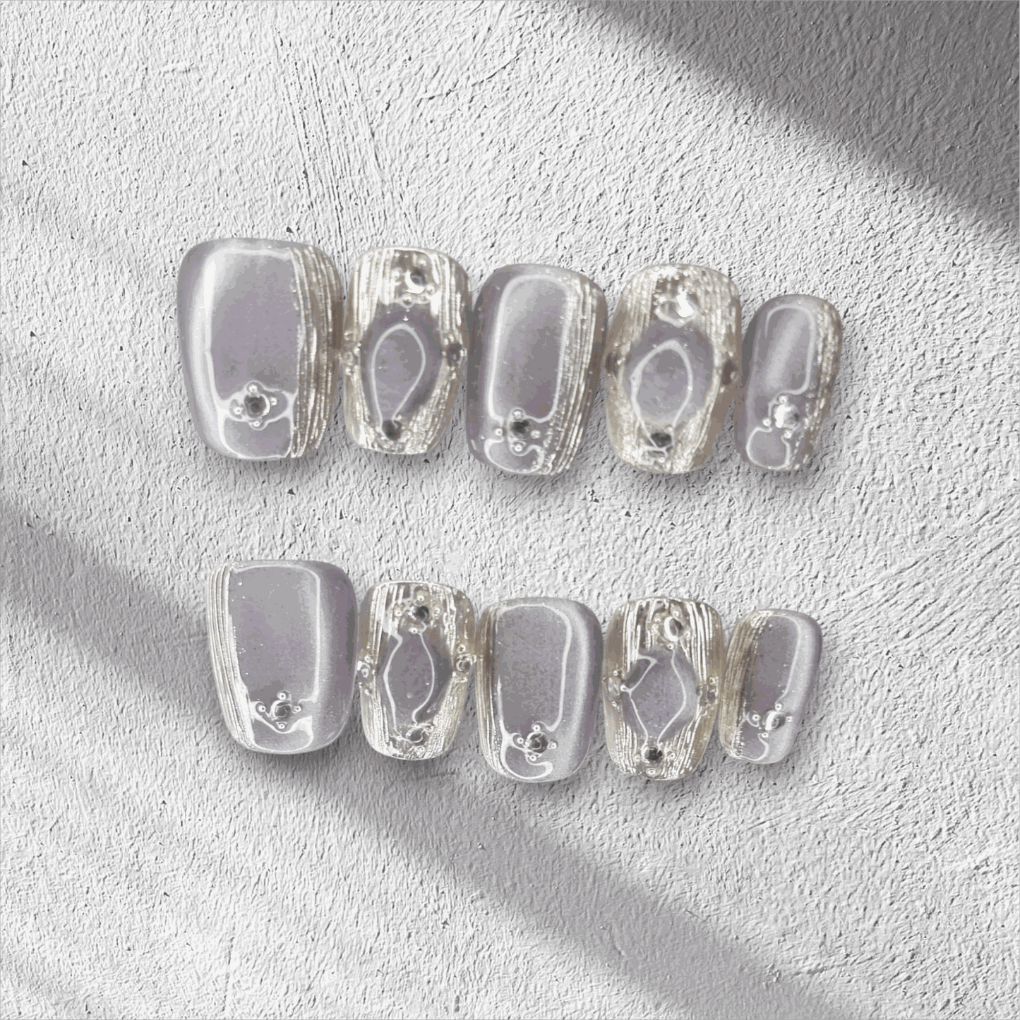 The Diriyah Elegance press-on nail set in a short square shape, featuring a semi-transparent base with 3D water droplet and gem details.