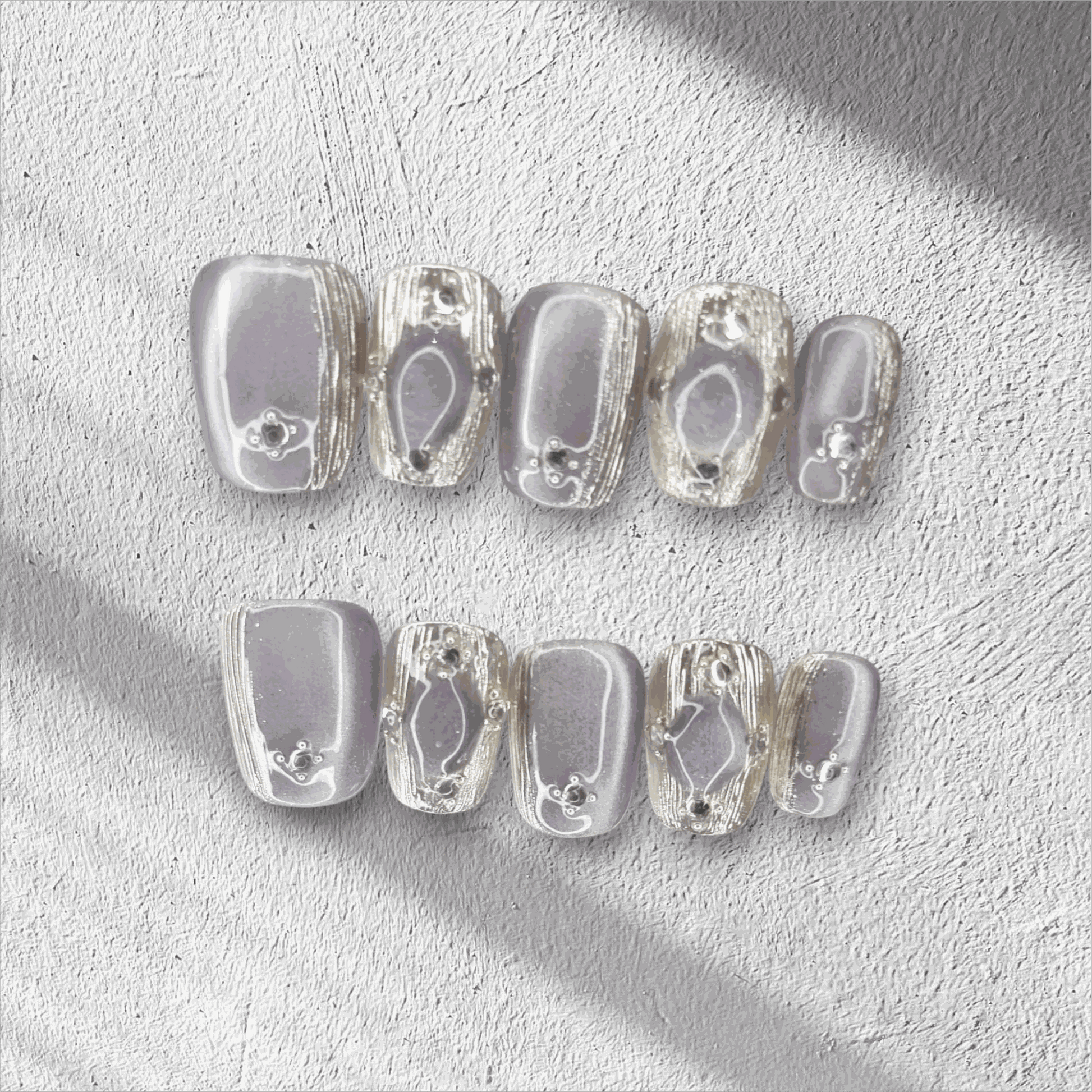 The Diriyah Elegance press-on nail set in a short square shape, featuring a semi-transparent base with 3D water droplet and gem details.