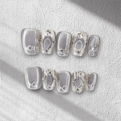 The Diriyah Elegance press-on nail set in a short square shape, featuring a semi-transparent base with 3D water droplet and gem details.