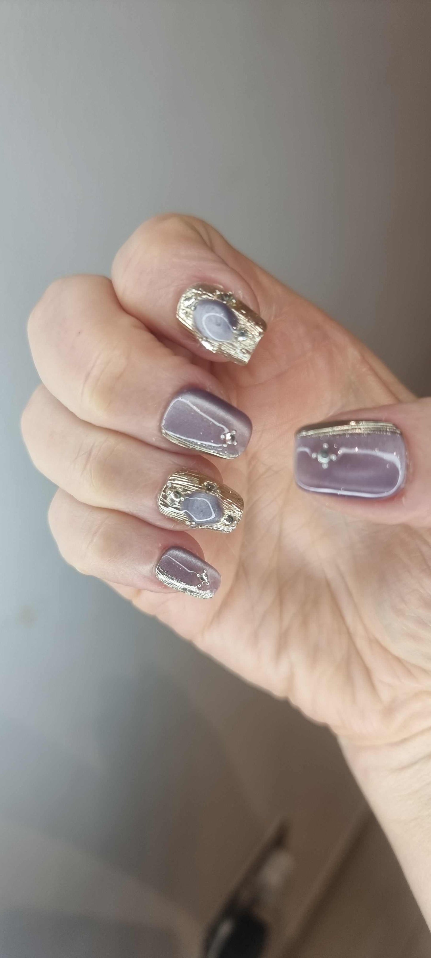 A model's hand wearing the chic Diriyah Elegance press-on nails, showcasing the unique 3D droplet effect.