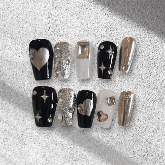 The Doha Dreams press-on nail set in a long coffin shape, featuring a mix of chrome, black, and silver glitter nails with 3D heart and star art.