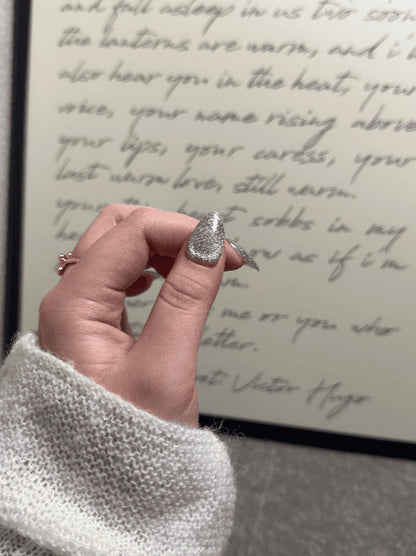 Hand holding a silver ring with a blurred handwritten text in the background