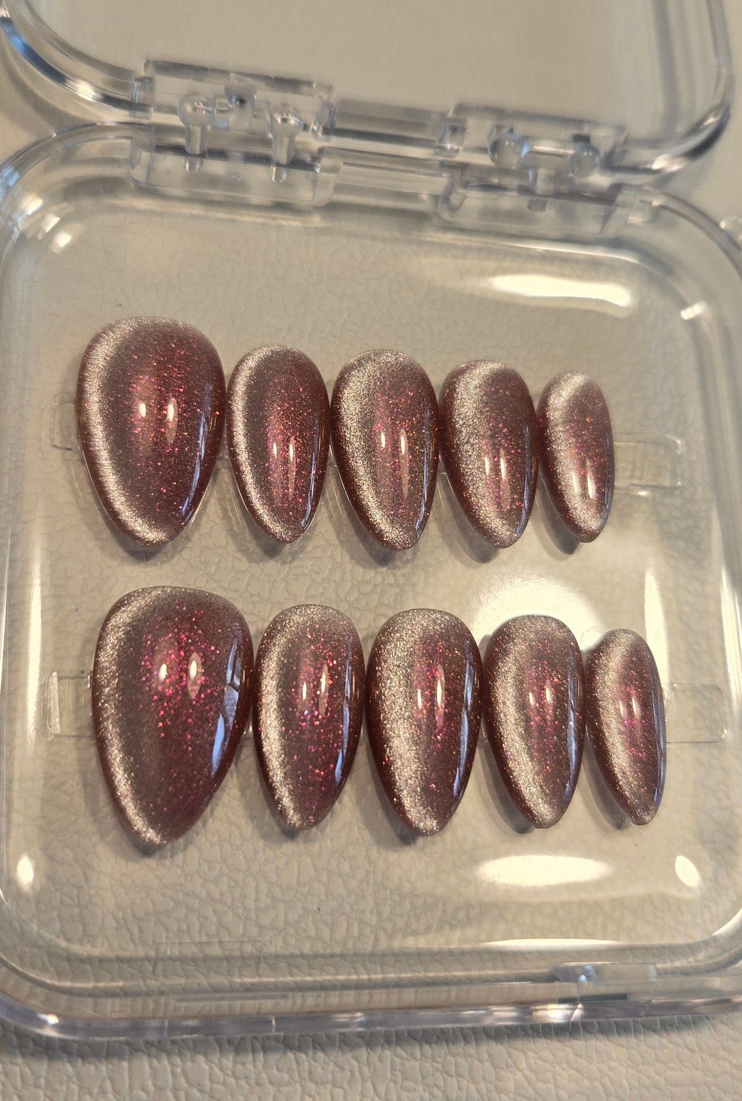 Set of metallic brown nail extensions in a clear plastic case.