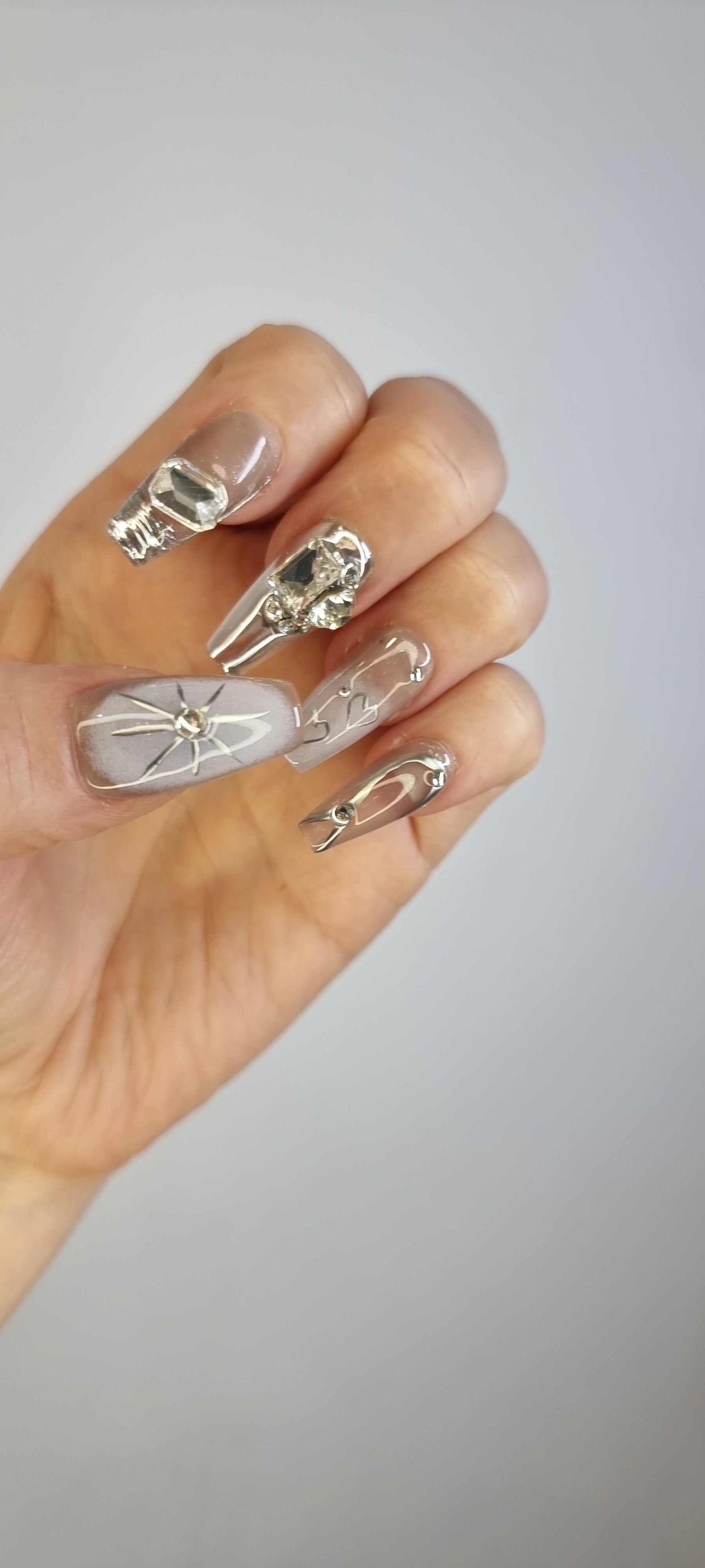 A model's hand wearing the avant-garde Habibi press-on nails, showcasing the unique 3D sculpted details.