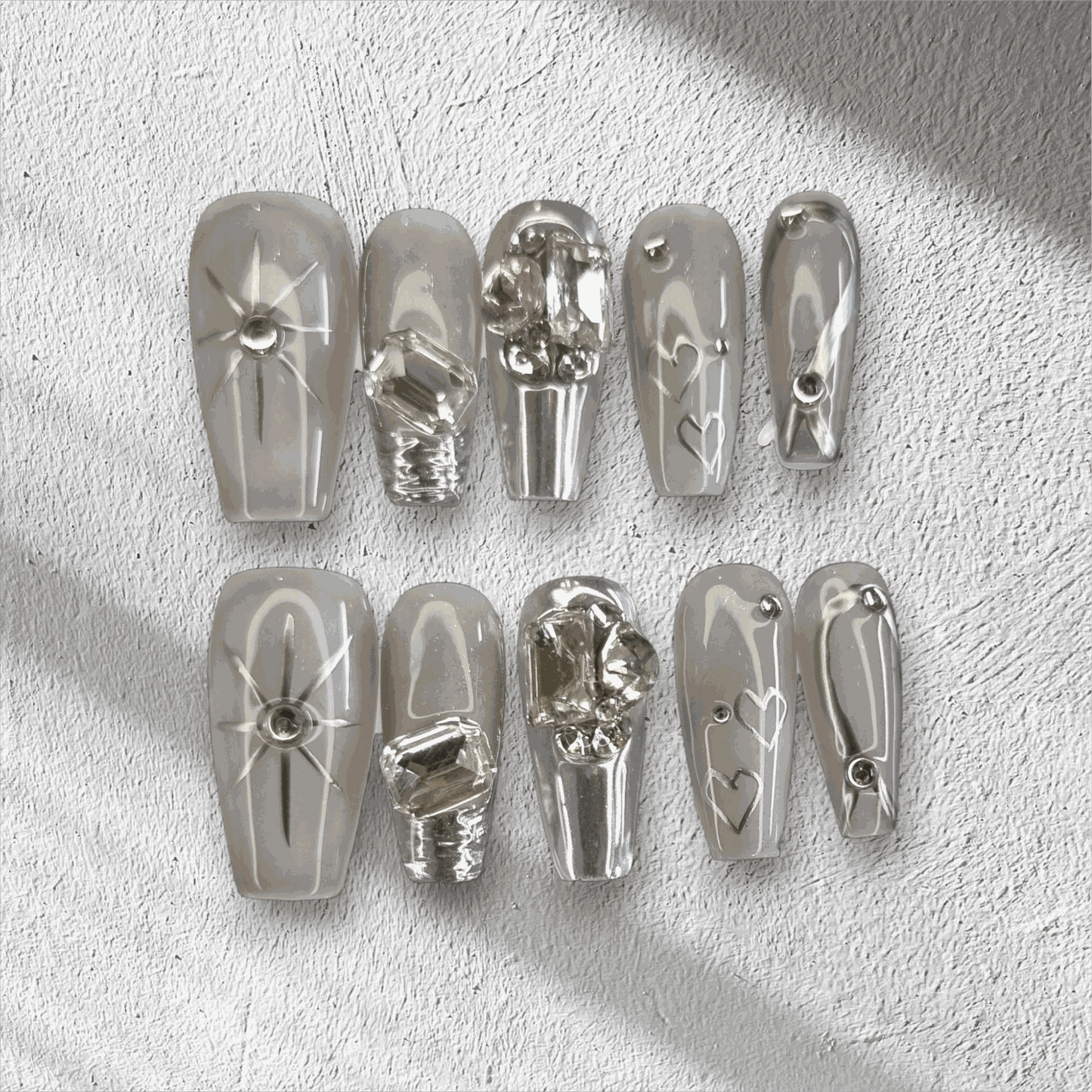 The Habibi press-on nail set in a long coffin shape, featuring intricate 3D sculpted faces and art on a semi-transparent base.