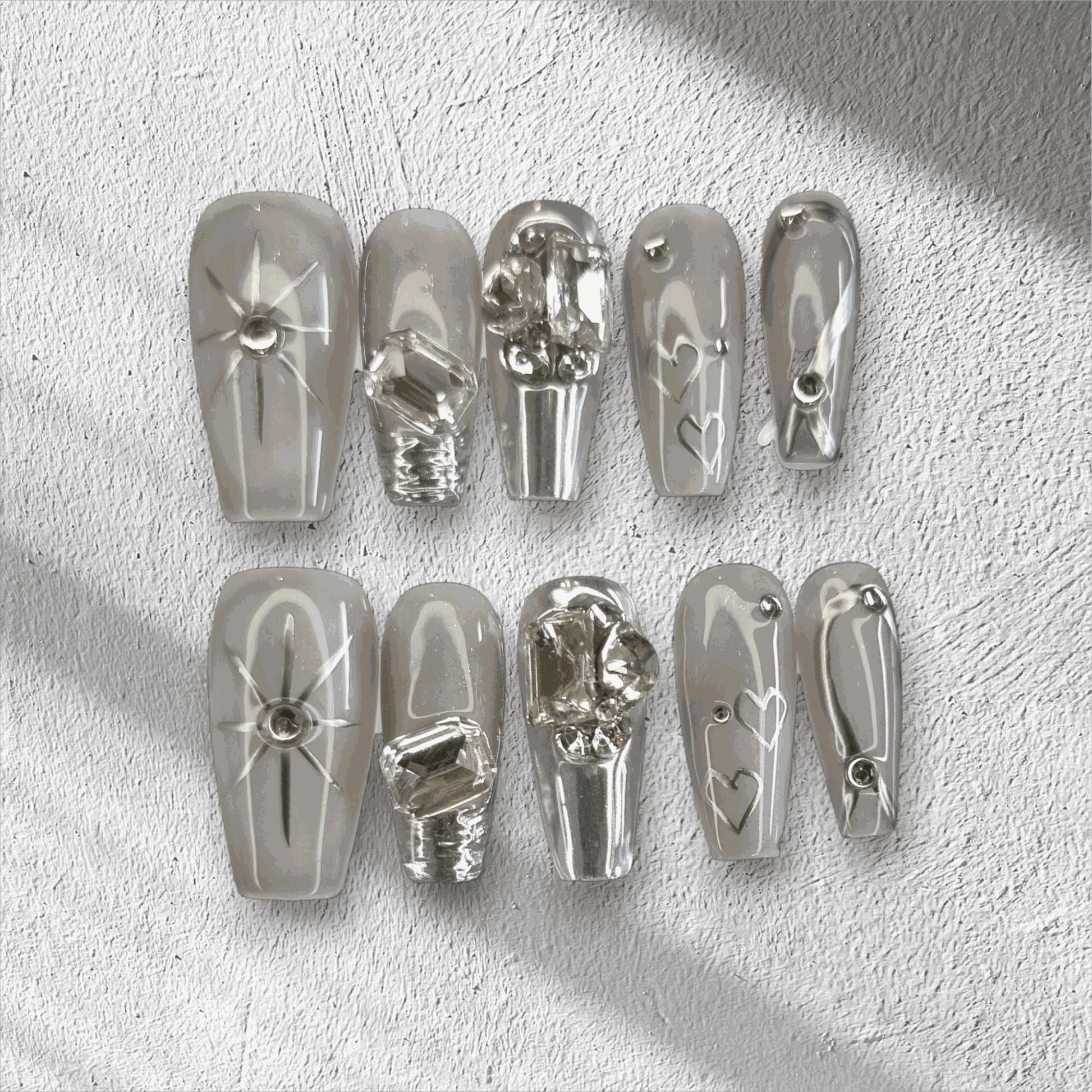 The Habibi press-on nail set in a long coffin shape, featuring intricate 3D sculpted faces and art on a semi-transparent base.