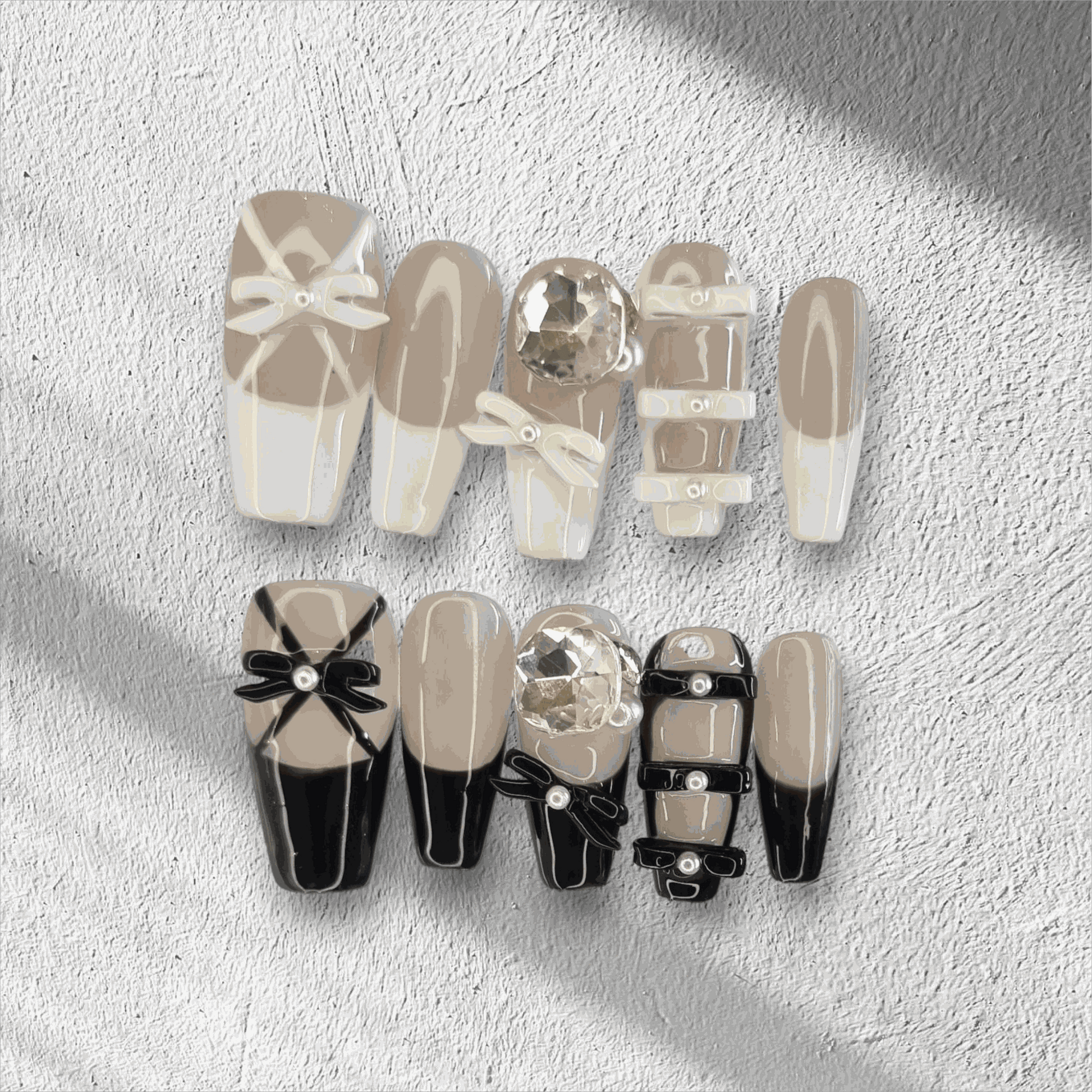 The Hasaas press-on nail set in a long coffin shape, featuring a mix of nude and black nails with large 3D bow and pearl embellishments.