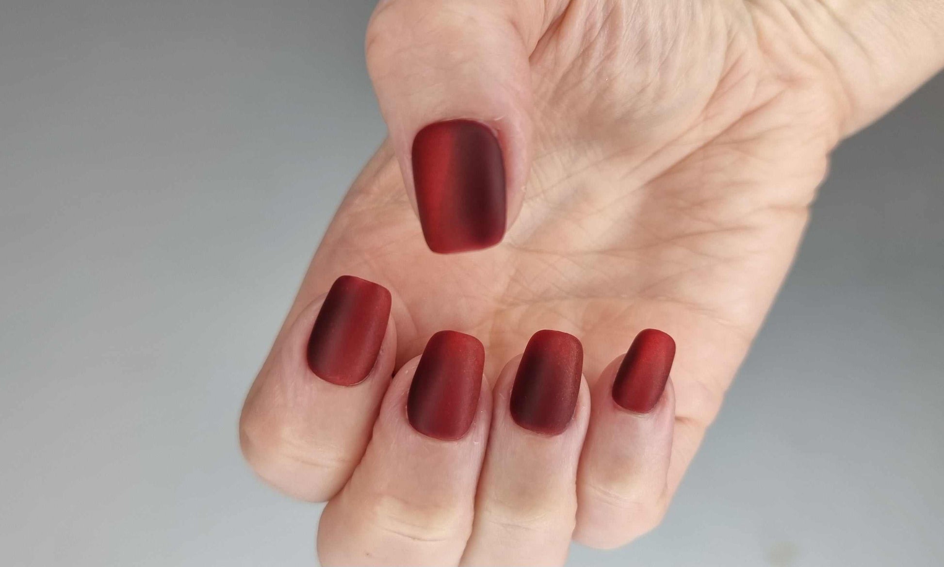 A close-up of the Hessa manicure, highlighting the rich red color and velvety matte texture of the press-on nails.