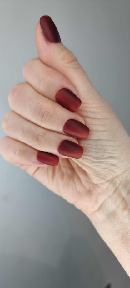 A model's hand wearing the sophisticated Hessa red matte press-on nails, showcasing the elegant square shape.