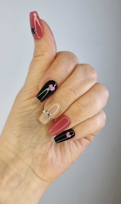 A close-up of the Hind long coffin press-on nails, highlighting the intricate heart artwork and sparkling rhinestone chain.