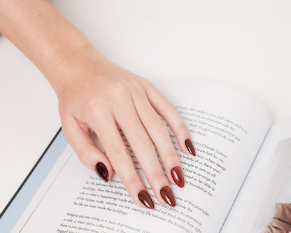 Hand with dark red nail polish on an open book