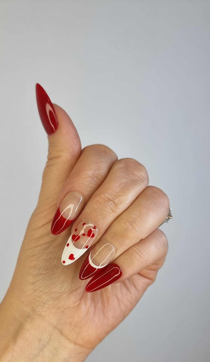 A manicure featuring the Holiday Romance almond press-on nails, highlighting the romantic and festive red and nude design.