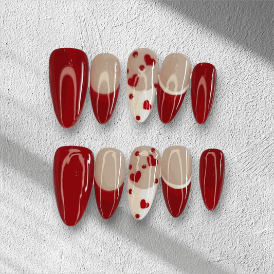 The Holiday Romance press-on nail set in a long almond shape, featuring a mix of solid red, nude, and red heart designs.