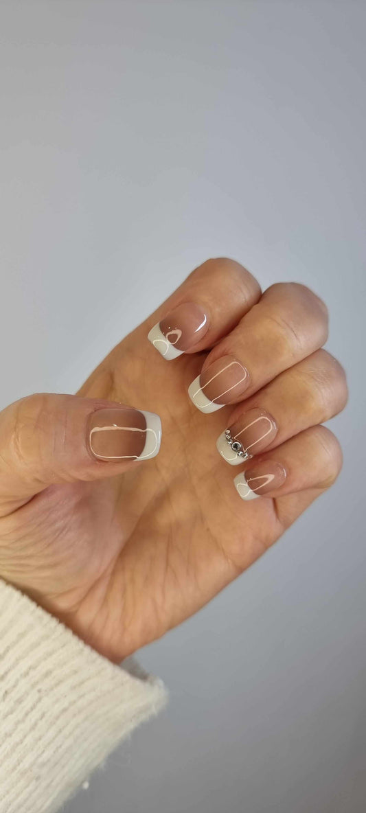 Hand wearing Hues of Hatta short square press-on nails with a brown ombre effect and a silver rhinestone chain.