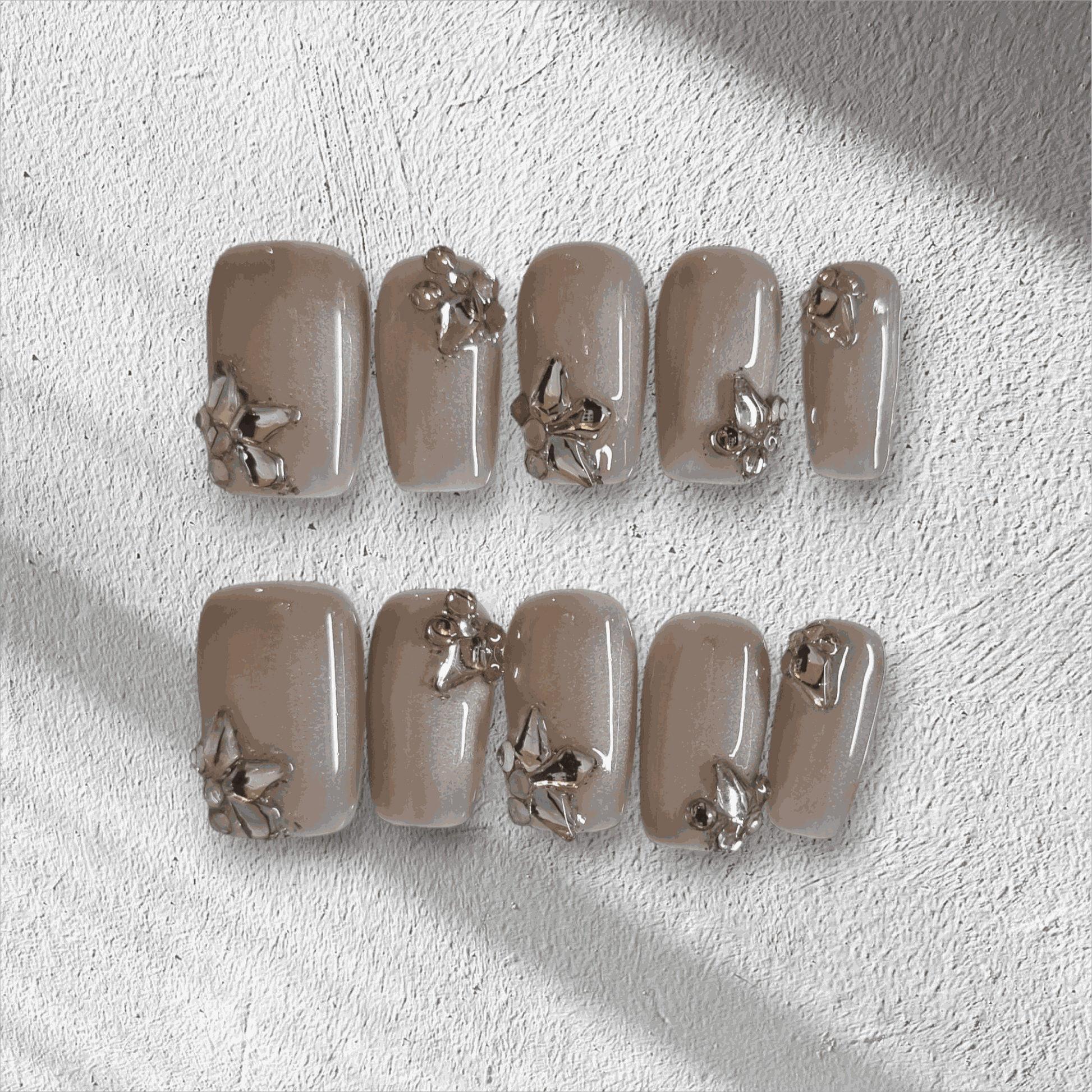 Jeddah Glow pearlescent nude short square press-on nails by Nail Addict, featuring shiny silver 3D flower and leaf accents.