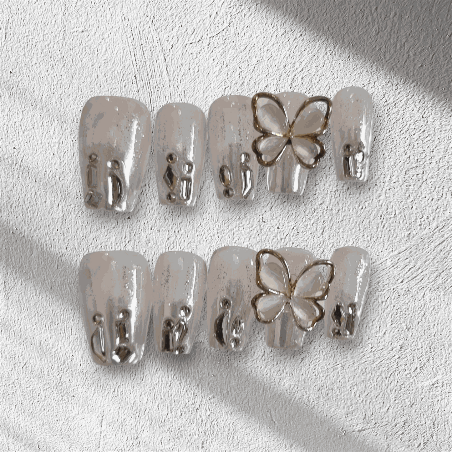 Jessie nude glitter coffin press-on nails by Nail Addict, featuring silver liquid-effect accents and a 3D butterfly charm.