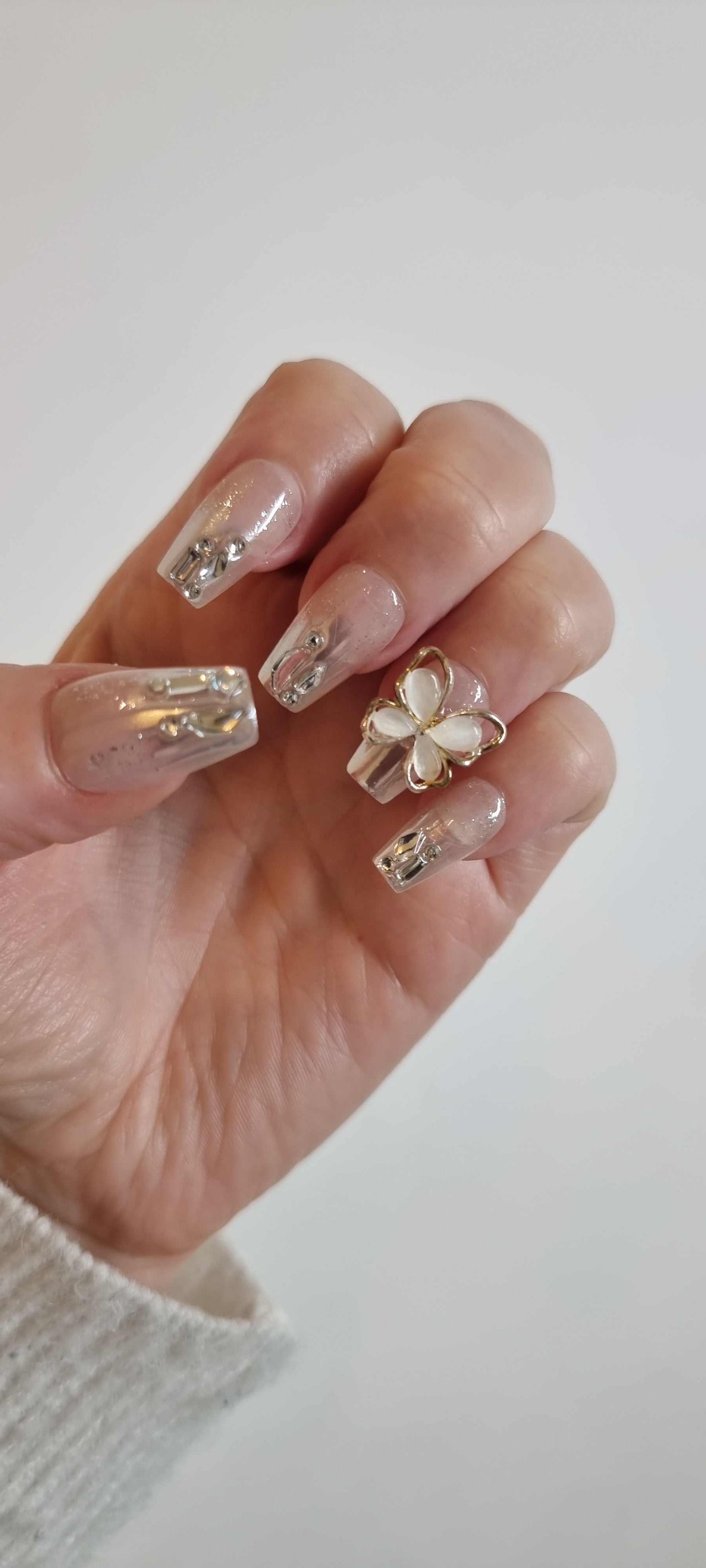Hand wearing Jessie nude and silver coffin press-on nails, showcasing the liquid-effect accents and 3D butterfly on the ring finger.