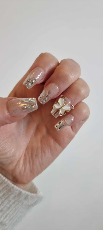 Hand wearing Jessie nude and silver coffin press-on nails, showcasing the liquid-effect accents and 3D butterfly on the ring finger.