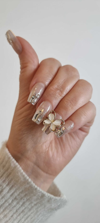  Hand wearing Jessie press-on nails by Nail Addict, highlighting the long coffin shape and elegant 3D butterfly charm.