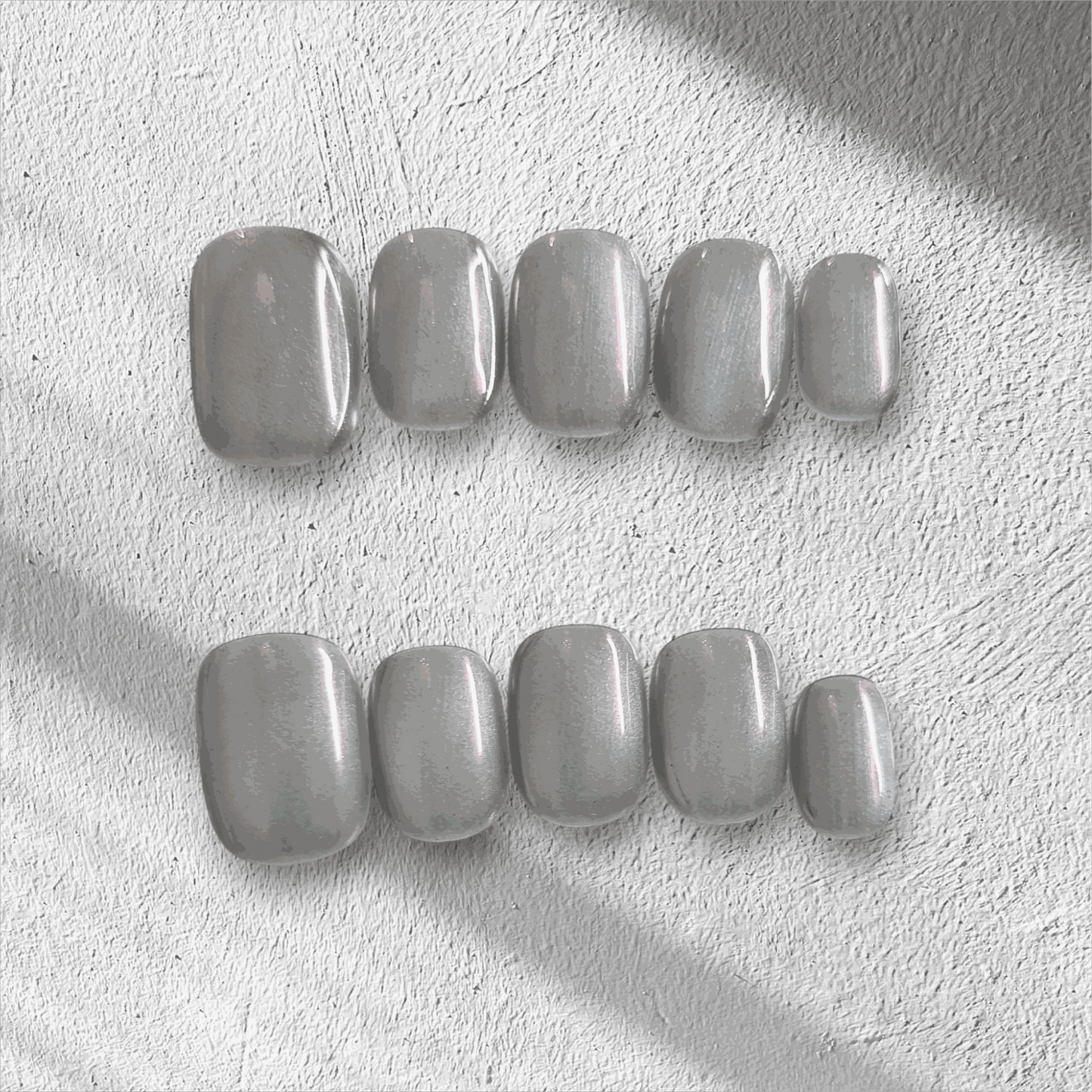 Lujain pearlescent gray-silver short oval press-on nail set displayed in the box.