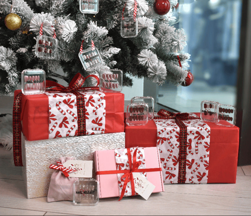 Christmas presents under a decorated tree with red ribbons and clear glass ornaments.