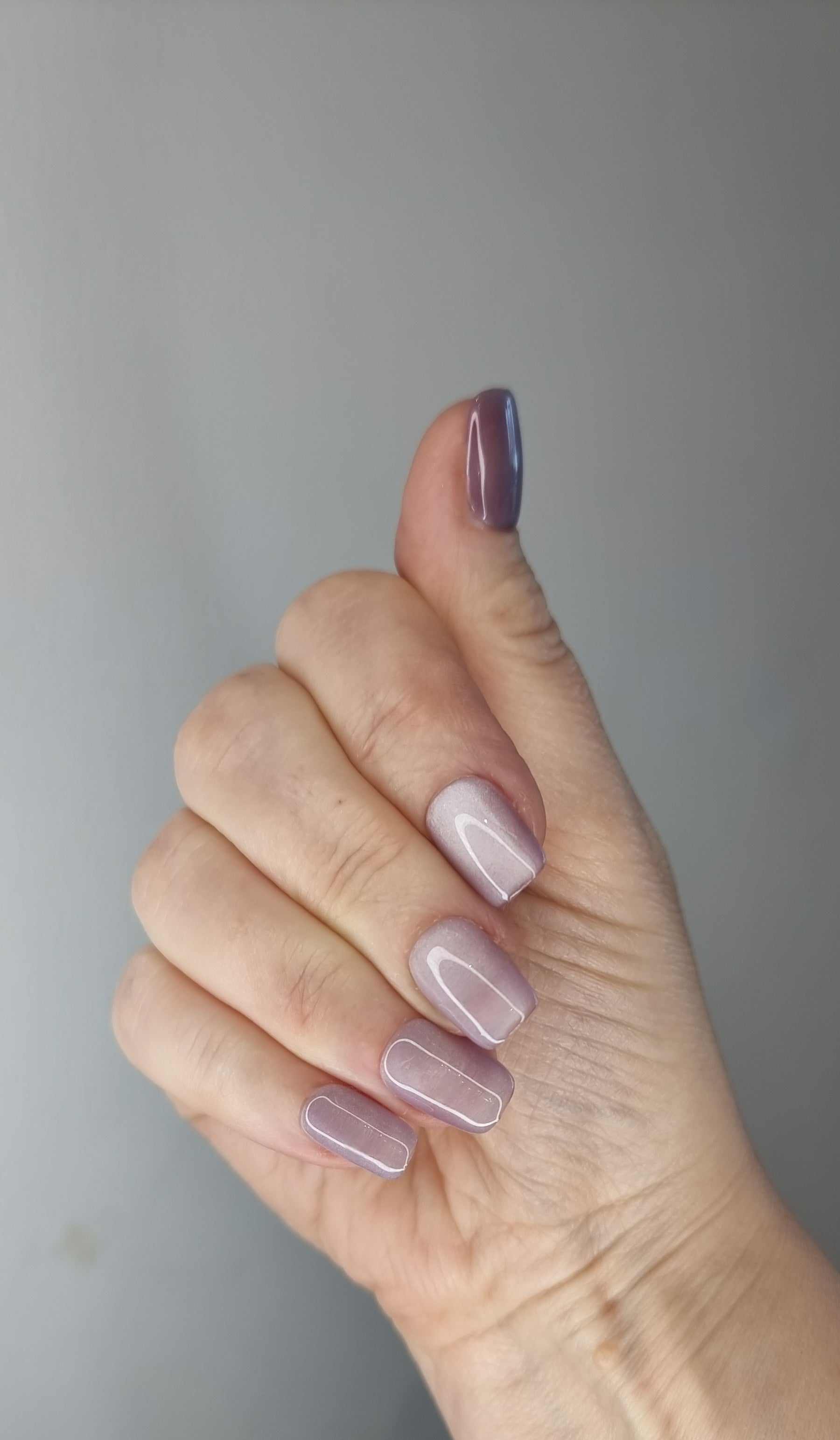 Hand wearing Manama Majesty short press-on nails with a black French tip, a white bow, and pearl accents.