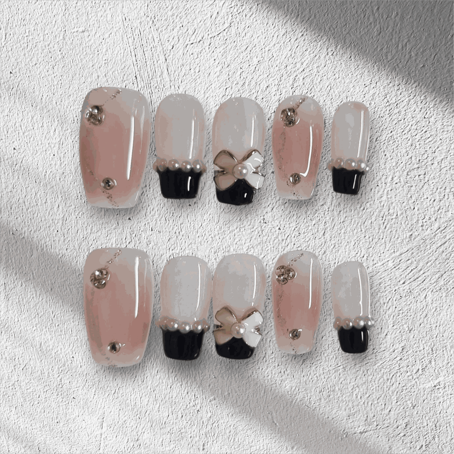 Mecca Magic black and nude almond press-on nails with bow detail by Nail Addict.