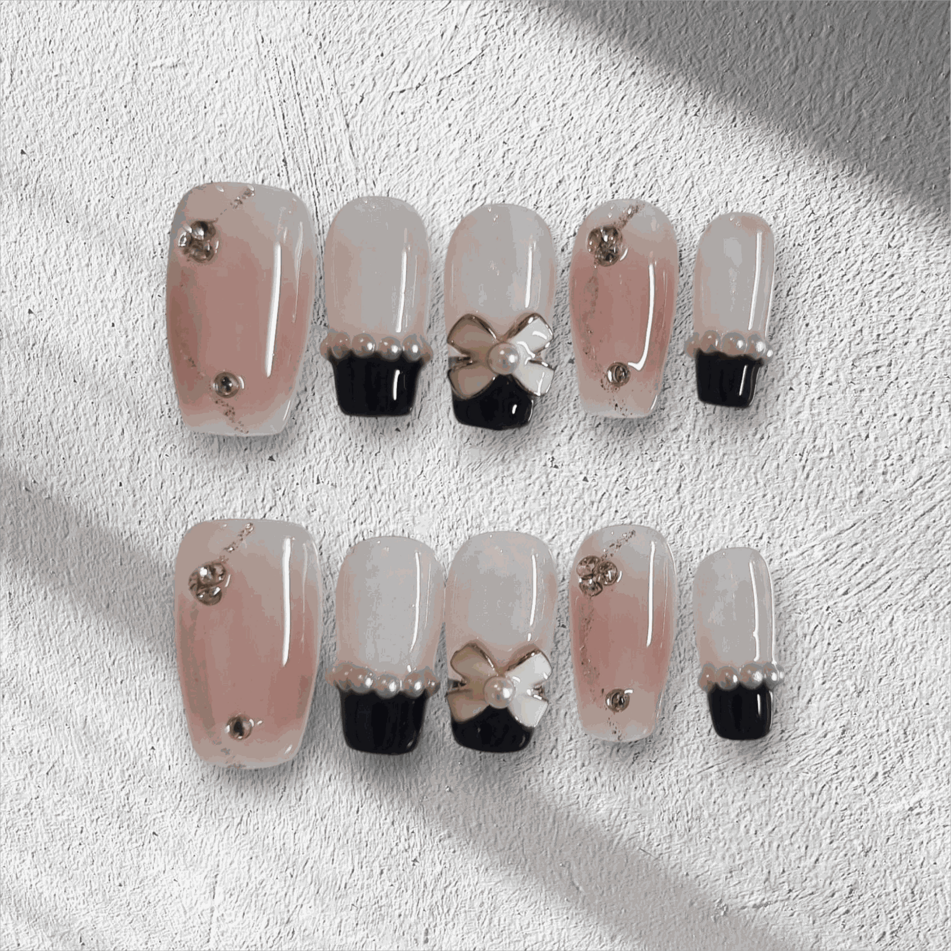 Mecca Magic black and nude almond press-on nails with bow detail by Nail Addict.