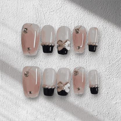 Mecca Magic black and nude almond press-on nails with bow detail by Nail Addict.