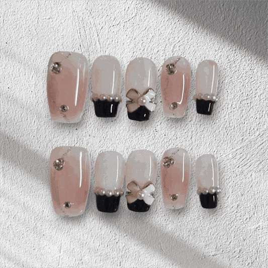 Mecca Magic black and nude almond press-on nails with bow detail by Nail Addict.