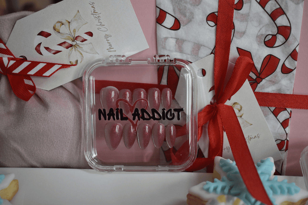 Nail art kit with 'Nail Addict' branding on a festive background with candy canes and gift wrap.