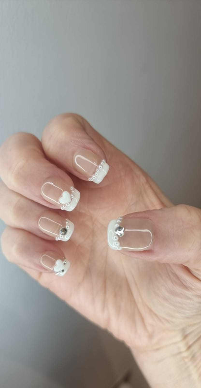 A model's hand wearing the Burj Beauty French manicure press-on nails, showcasing the elegant rhinestone detail.