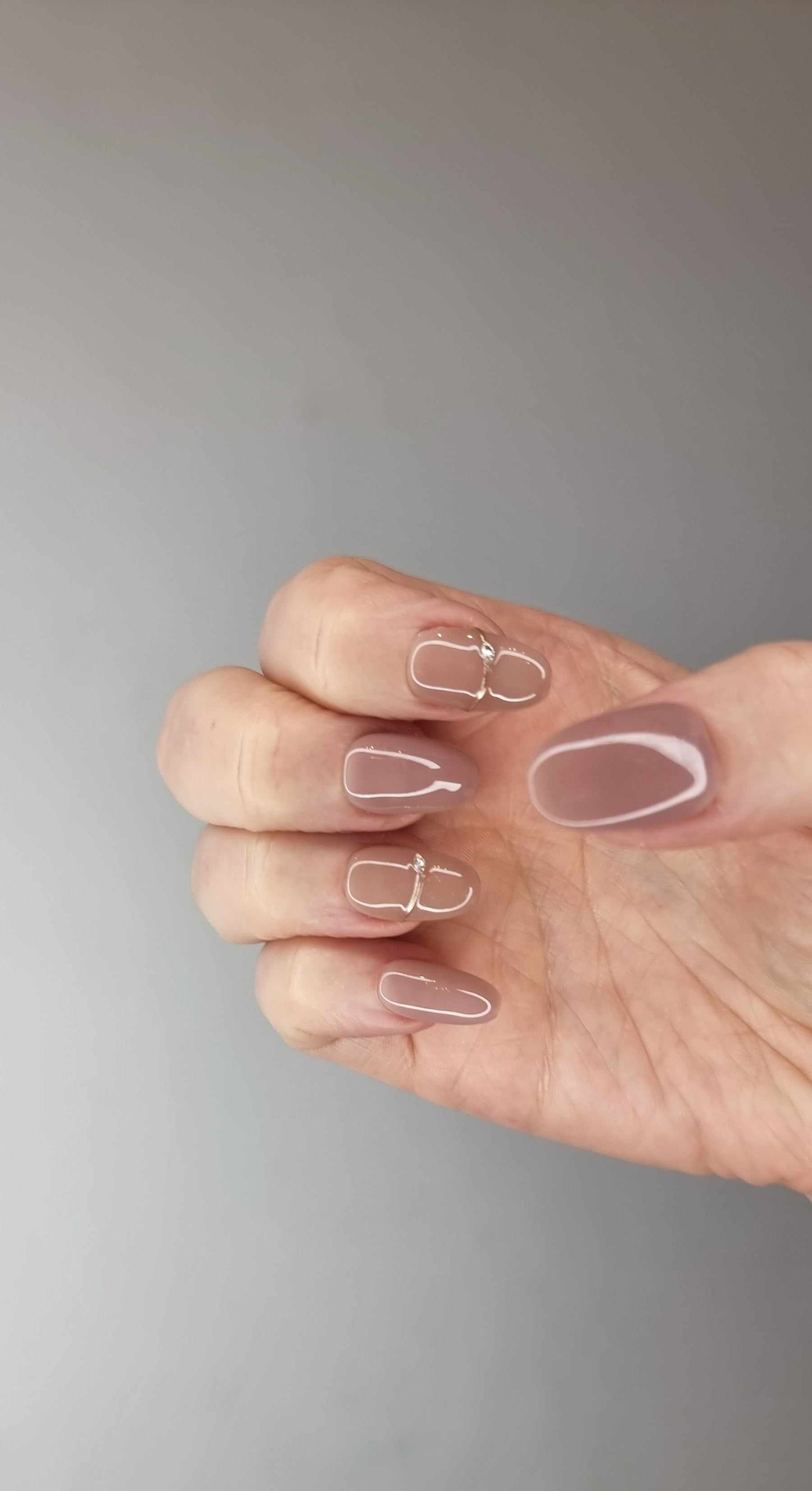 Close-up of a hand showcasing almond-shaped Munira nails painted in a matte finish.