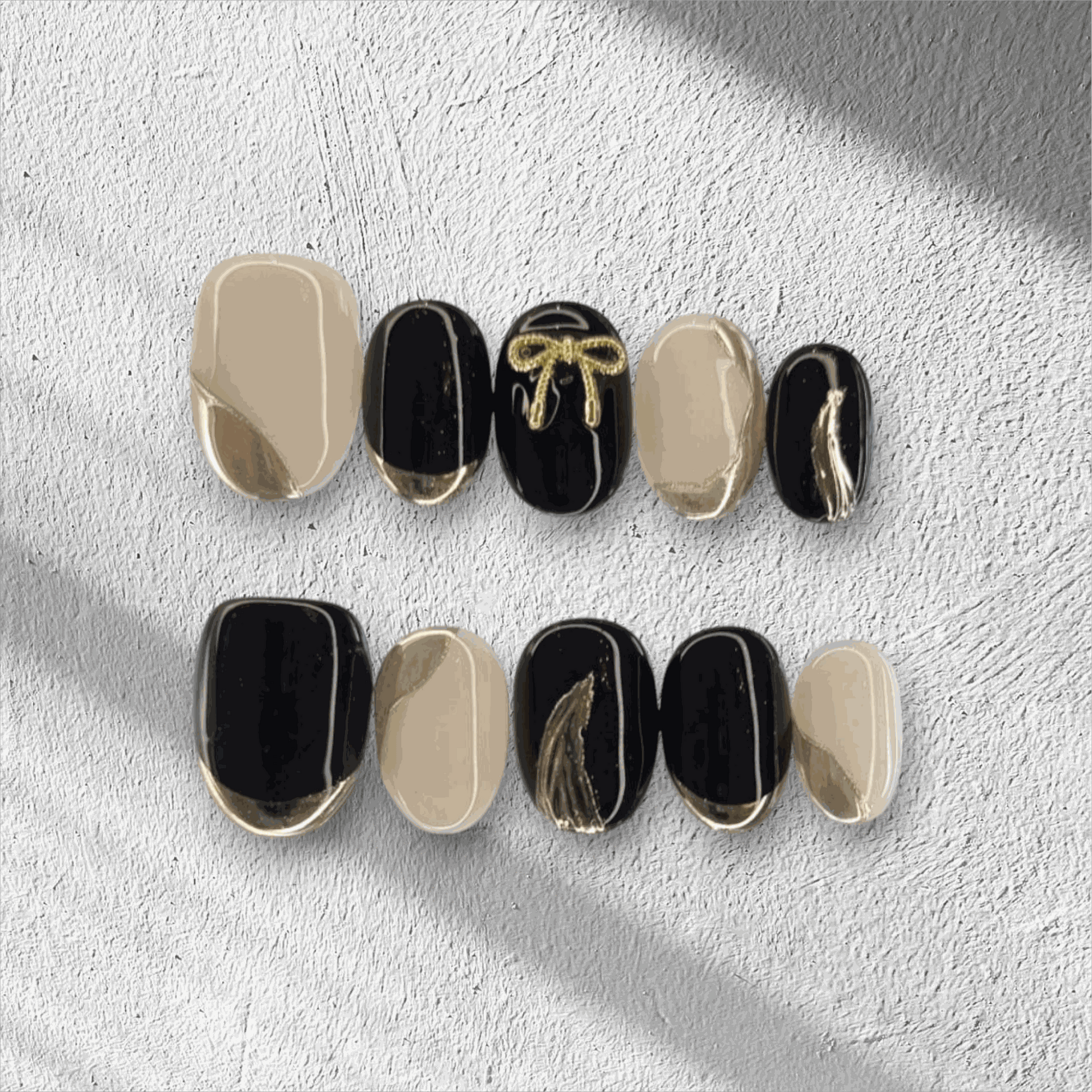 Full set of Muscat Mystique black and nude almond press-on nails displayed in the box.