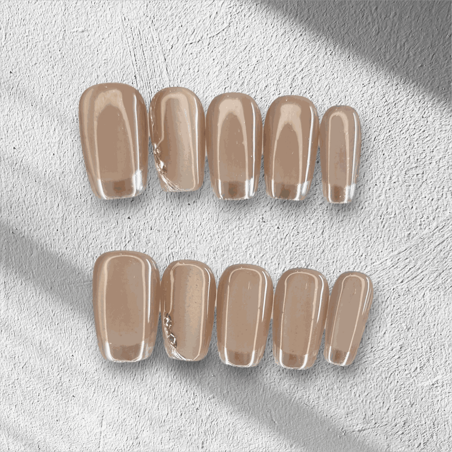 A flat lay of the long, glossy, clear nude Nahla press-on nail set displayed in the box.
