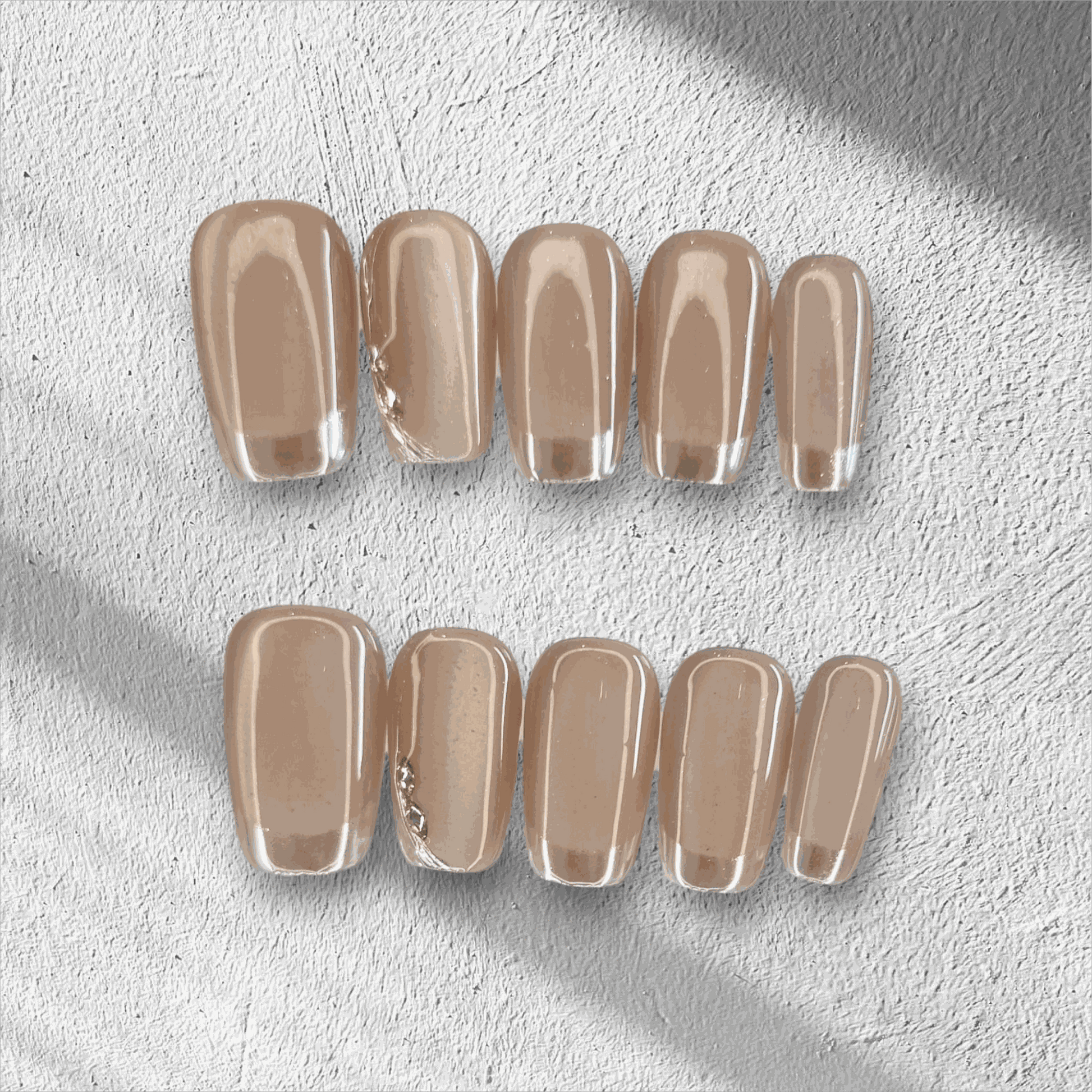 A flat lay of the long, glossy, clear nude Nahla press-on nail set displayed in the box.