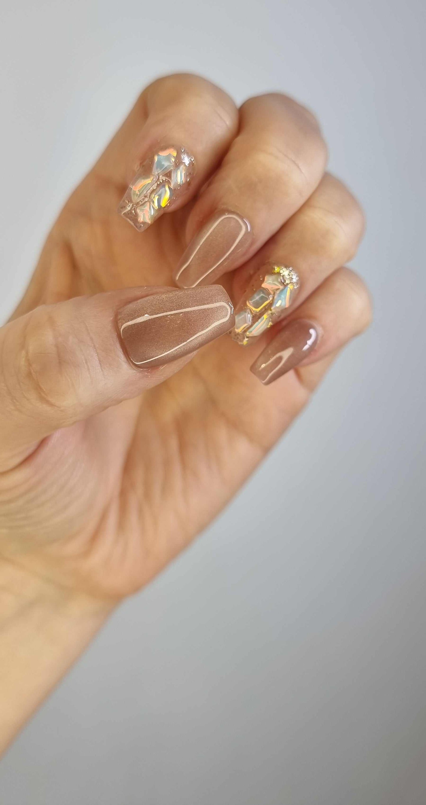 A flat lay of the shiny, almond-shaped Najma press-on nails, showing metallic detail.