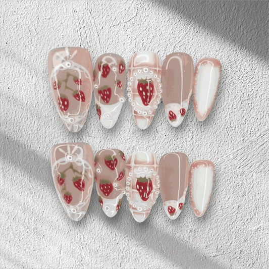 Omani Oasis press-on nails in a long almond shape, featuring a charming hand-painted strawberry design with white lace and pearl details on a nude base.