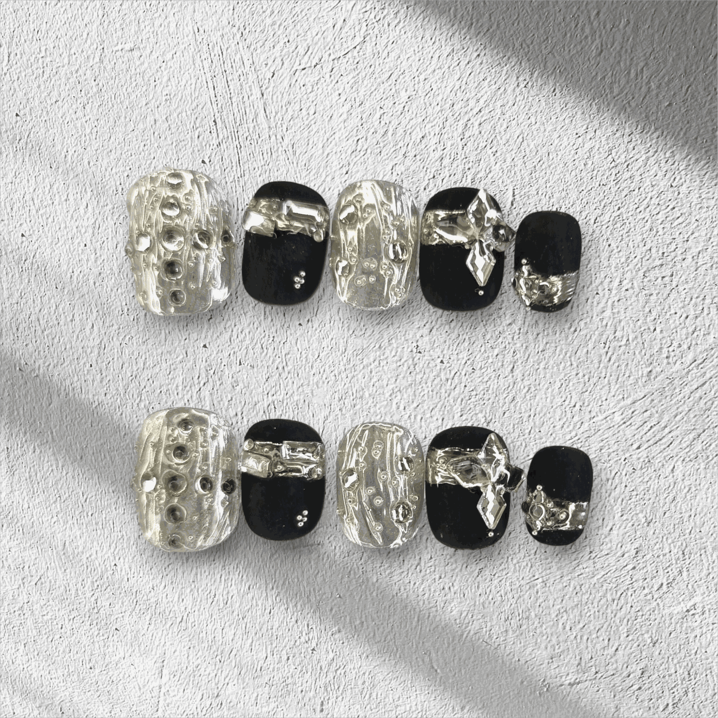 Full set of black and silver glossy press-on nails from the Qatar Elegance collection displayed in the box.