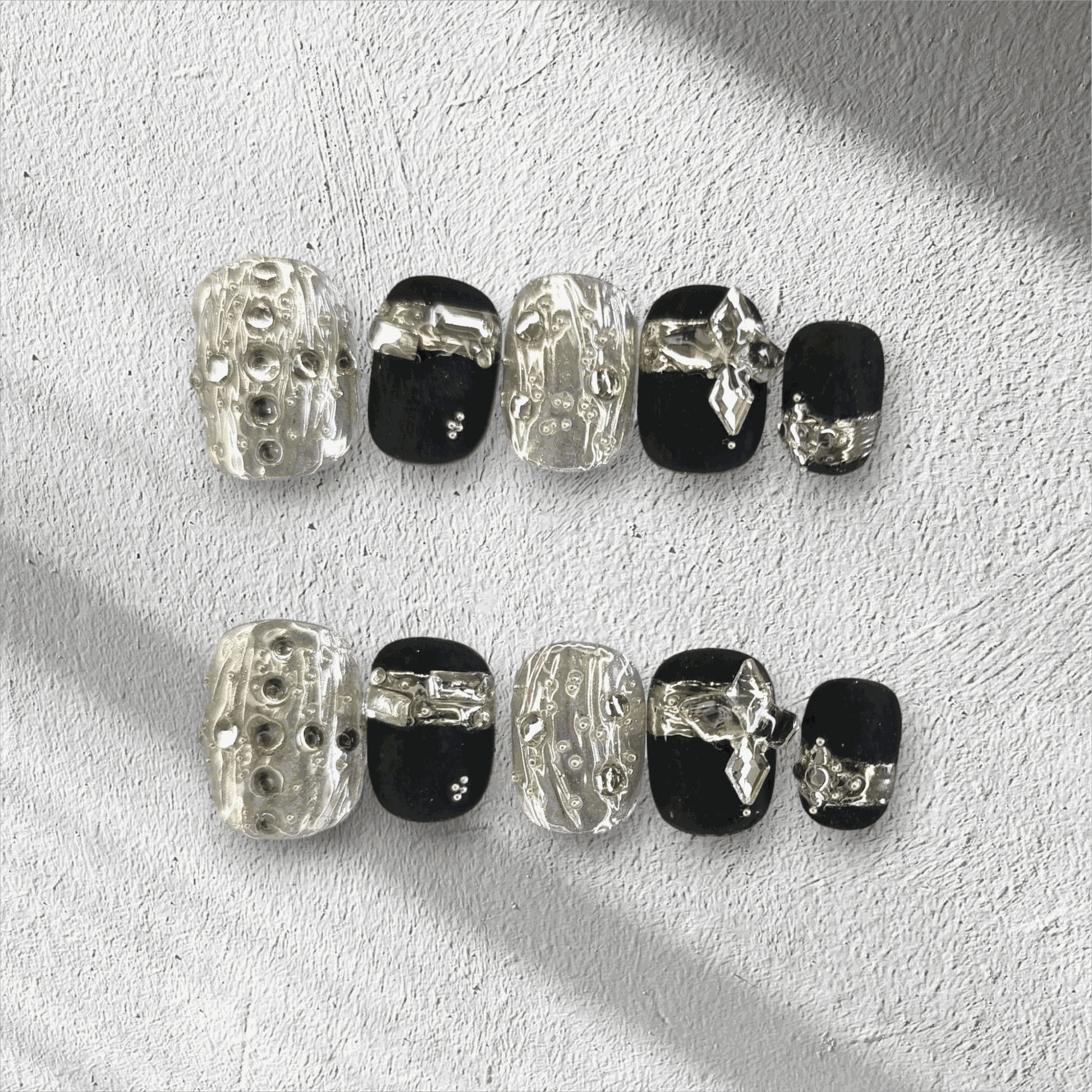 Full set of black and silver glossy press-on nails from the Qatar Elegance collection displayed in the box.