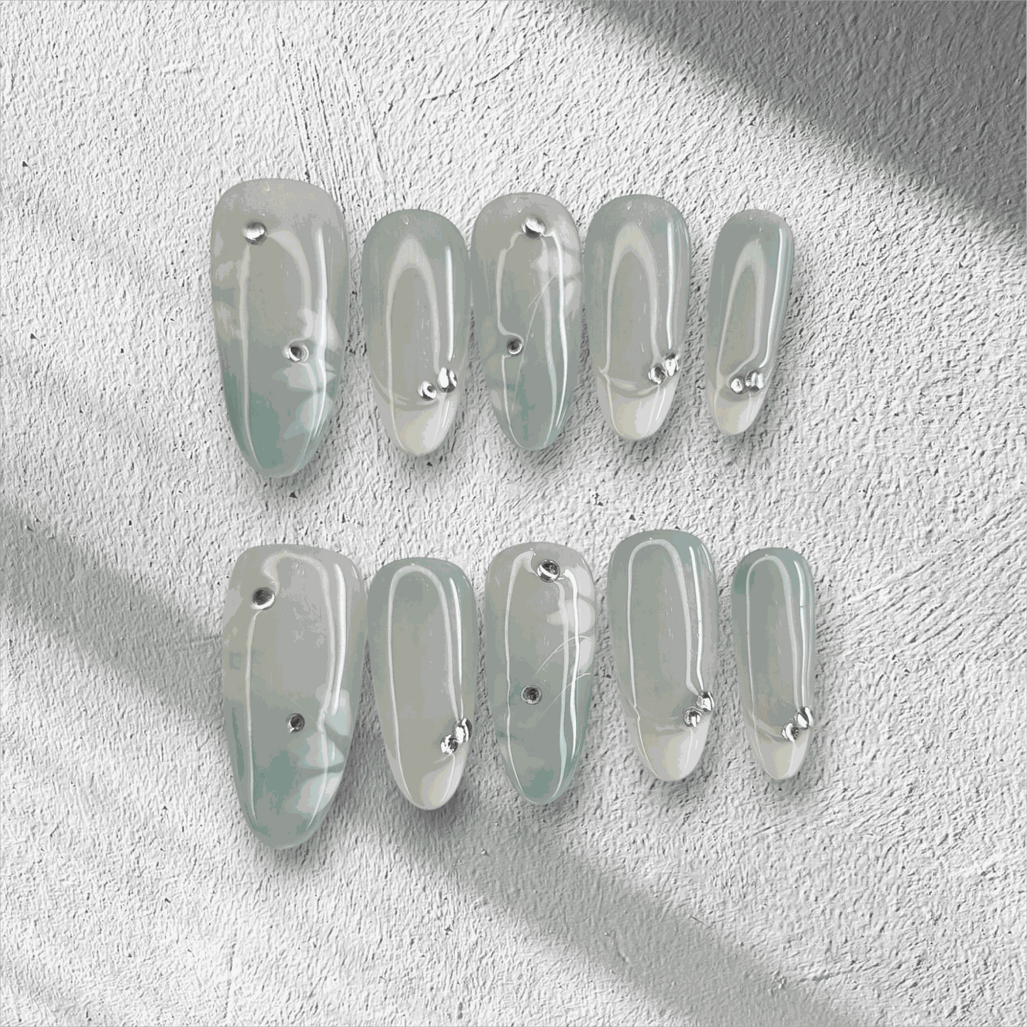 Full set of glossy, translucent off-white Rawan press-on nails displayed in the box.