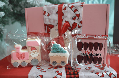 Holiday-themed nail art set with decorative cookies and a pink box.