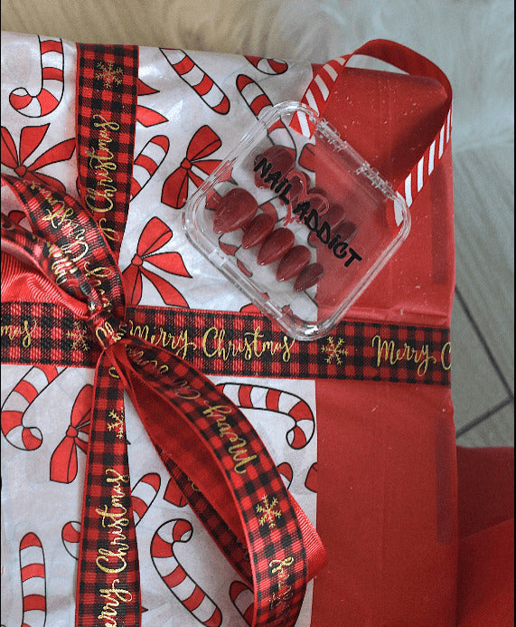 Nail art kit with 'Nail Addict' packaging on a Christmas-themed gift bag.