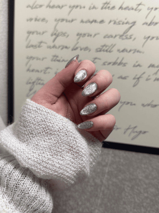 Hand with silver nail polish in front of handwritten text