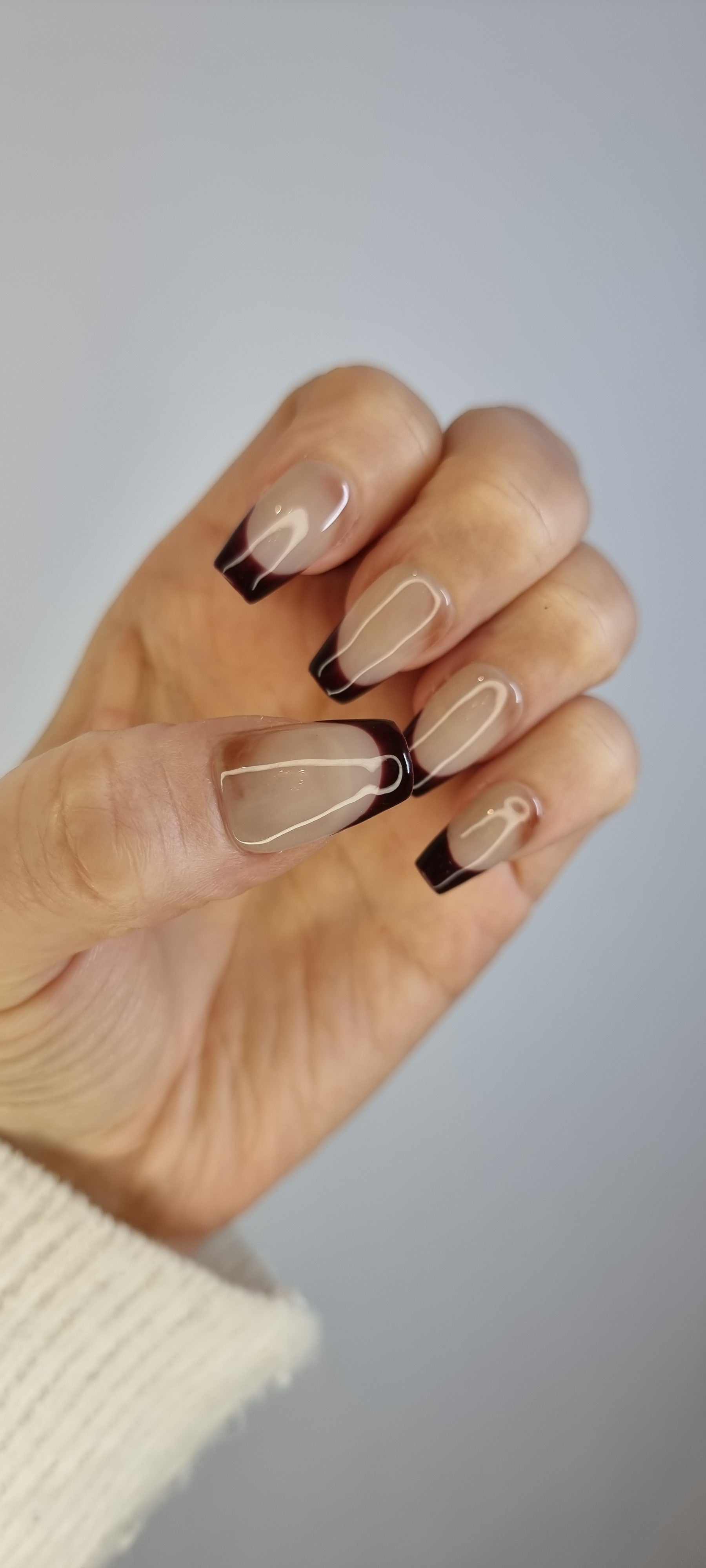 A model's hand wearing the modern Riham press-on nails.