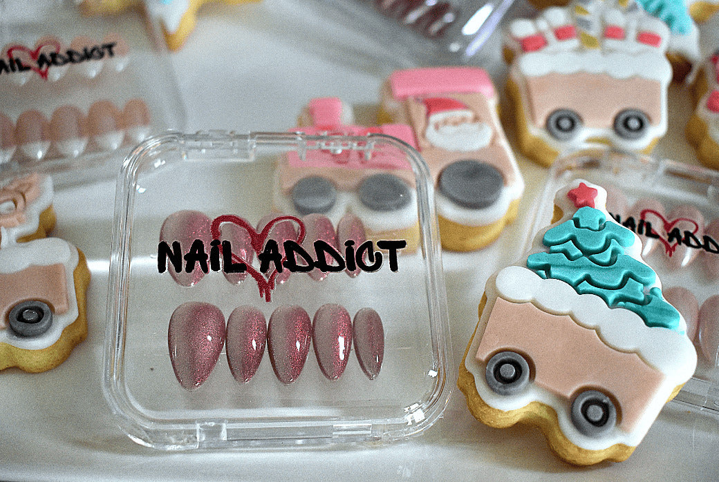 Nail art display with 'Nail Addict' packaging and decorative cookies in the background
