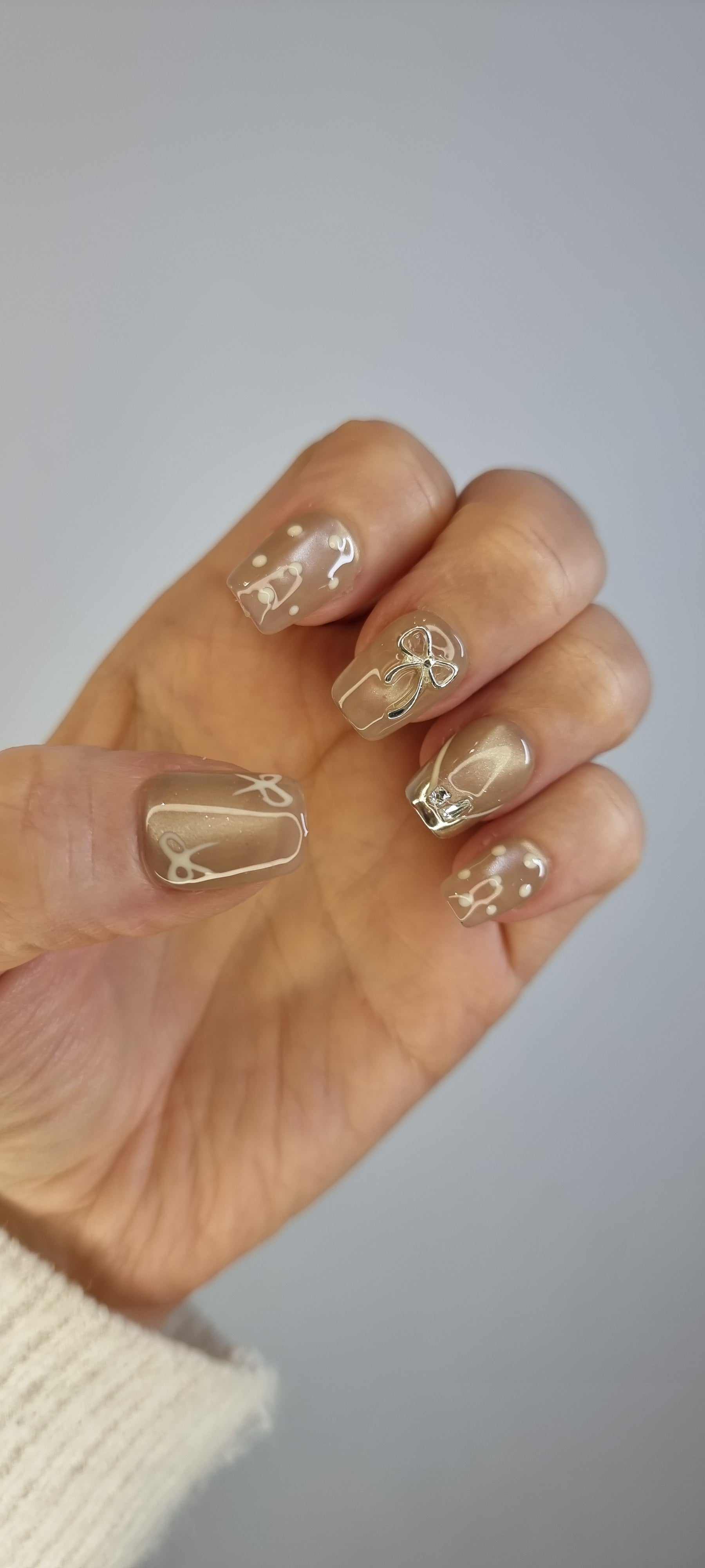 Close-up of Sahara false nails with a metallic champagne color and glossy finish.