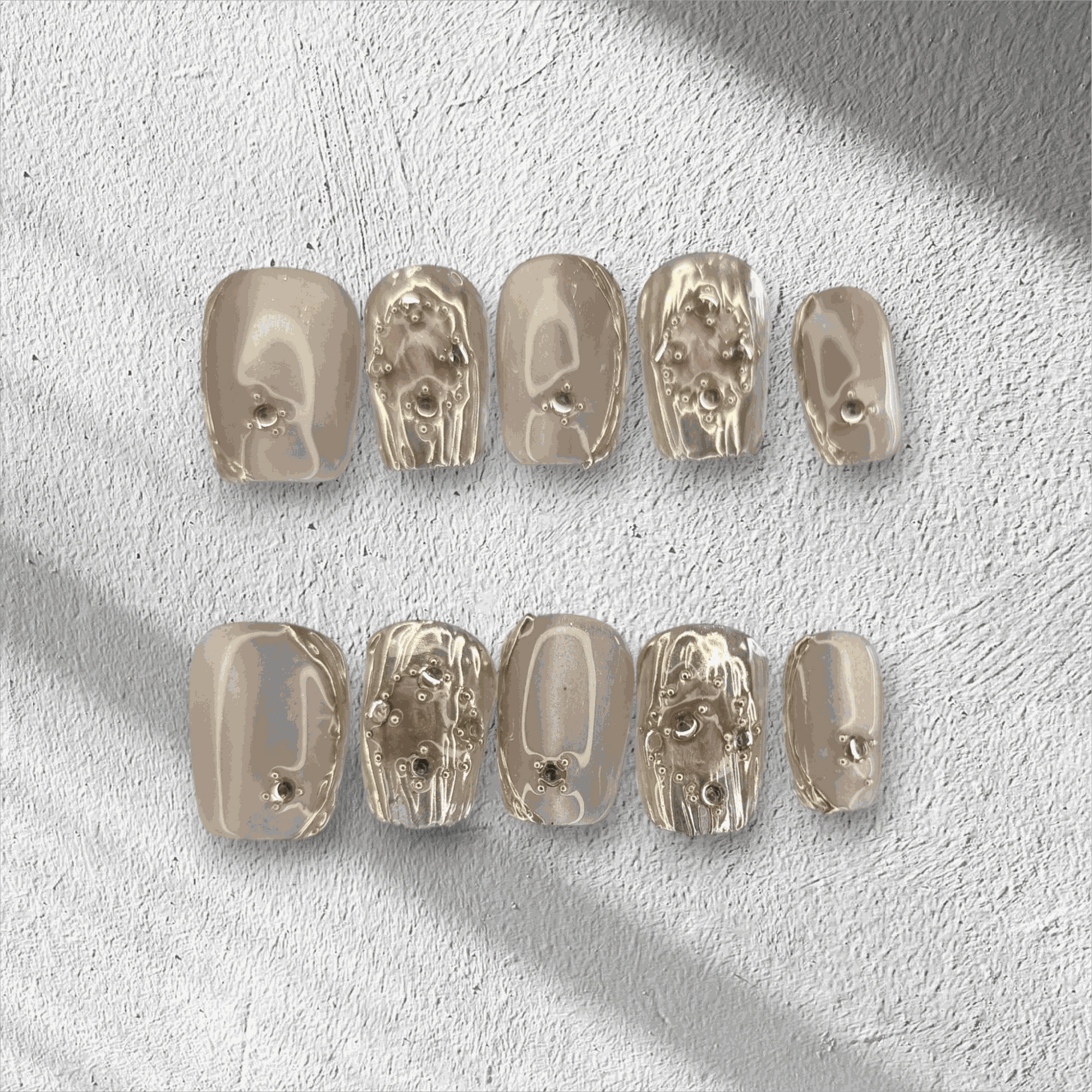 Full set of metallic gold, coffin-shaped Sama Short press-on nails displayed in the box.