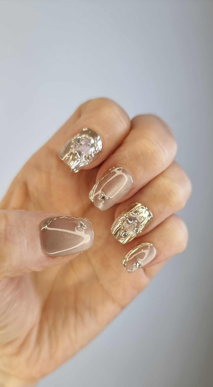Close-up of metallic gold, coffin-shaped Sama Short press-on nails.