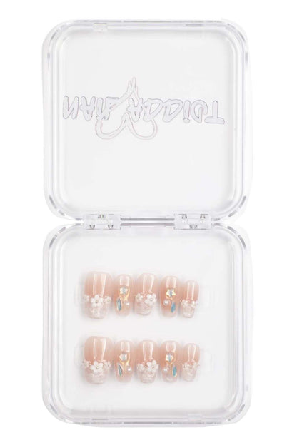 Selina sheer pink and white short square press-on nails by Nail Addict, with a heart charm accent.